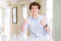 Young business man with curly read head success sign doing positive gesture with hand, thumbs up smiling and happy Royalty Free Stock Photo