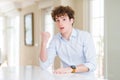 Young business man with curly read head Surprised pointing with hand finger to the side, open mouth amazed expression Royalty Free Stock Photo