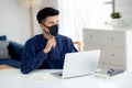 Young business man in face mask planning and working from home on laptop computer on desk for protection for outbreak. Royalty Free Stock Photo