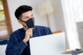Young business man in face mask planning and working from home on laptop computer on desk for protection. Royalty Free Stock Photo