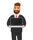 Young business man in formal wear suit holding or showing the blank screen of a laptop computer in hands. Modern lifestyle. Royalty Free Stock Photo