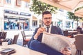 Young business man with glass of water in hand reading newspaper at outdoor cafe Royalty Free Stock Photo