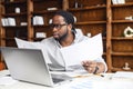 Young business man in glasses looking through workpaper