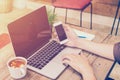 Young business man hand holding phone and using laptop in coffee Royalty Free Stock Photo