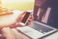 Young business man hand holding phone and using laptop computer Royalty Free Stock Photo