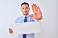 Young business man holding blank banner over isolated background with open hand doing stop sign with serious and confident Royalty Free Stock Photo