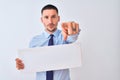 Young business man holding blank banner over isolated background pointing with finger to the camera and to you, hand sign, Royalty Free Stock Photo