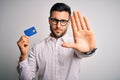 Young business man holding credit card over isolated background with open hand doing stop sign with serious and confident Royalty Free Stock Photo