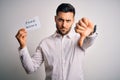 Young business man holding fake news paper over isolated background with angry face, negative sign showing dislike with thumbs Royalty Free Stock Photo