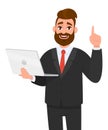 Young business man holding/showing latest brand new laptop computer device and pointing finger up or gesturing/showing number one. Royalty Free Stock Photo