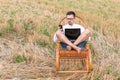 Young business man holding smartphone while working at the computer in a rocking chair. Adult man downshifter working at