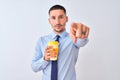 Young business man holding take away coffee over isolated background pointing with finger to the camera and to you, hand sign, Royalty Free Stock Photo