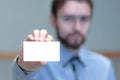 Young business man holding white business card on modern office blur background Royalty Free Stock Photo