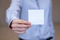 Young business man holding white business card on modern office blur background Royalty Free Stock Photo