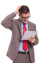 Young business man holds tablet and scratches head Royalty Free Stock Photo