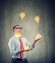 Young business man juggling with new ideas light bulbs