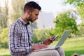 Young business man with laptop working in the park near office building Royalty Free Stock Photo