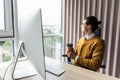 Young business man looking at pc computer screen and holding coffee cup in office Royalty Free Stock Photo