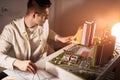 Young business man measuring a model of high building