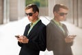 Young business man with a mobile phone standing at the wall Royalty Free Stock Photo