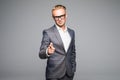 Young business man in glasses pointing and looking at the camera. on a gray background Royalty Free Stock Photo