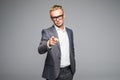 Young business man in glasses pointing and looking at the camera. on a gray background Royalty Free Stock Photo