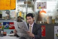 Young business man reading newspaper in fast food restaurant