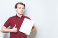 Young business man in red polo shirt holding blank A4 signboard paper showing thumb up . Business background with copy space Royalty Free Stock Photo