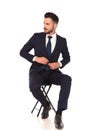 Young business man sitting on chair and buttoning his suit