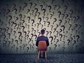 Business man sitting on a chair in front of a wall has many questions, wondering what to do next Royalty Free Stock Photo