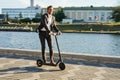 Young business man in a suit riding an electric scooter on a business meeting.