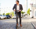 Young business man in a suit riding an electric scooter on a business meeting. Royalty Free Stock Photo