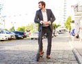 Young business man in a suit riding an electric scooter on a business meeting. Royalty Free Stock Photo
