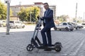 Young business man in a suit riding an electric scooter on business meeting. Ecological transportation concept. rent an Royalty Free Stock Photo