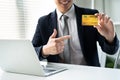 Young business man in a suit with a smile and pointing his finger at the yellow credit card. Royalty Free Stock Photo