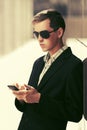 Young business man in sunglasses using smart phone on city street Royalty Free Stock Photo