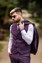 Young business man in sunglasses and wearing on violet luxery three-piece suit looks to side while walking on street Royalty Free Stock Photo