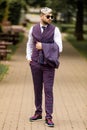 Young business man in sunglasses and wearing on violet luxery three-piece suit looks to side while walking on street Royalty Free Stock Photo