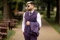 Young business man in sunglasses and wearing on violet luxery three-piece suit looks to side while walking on street Royalty Free Stock Photo