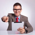 Young business man with tablet points at you and smiles Royalty Free Stock Photo