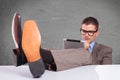 Young business man with tablet sits with feet on desk Royalty Free Stock Photo