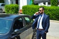 Young Business Man talking on the phone near the car