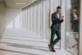 Young business man using mobile phone in the modern office hallway Royalty Free Stock Photo