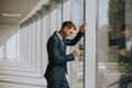 Young business man using mobile phone in the modern office hallway Royalty Free Stock Photo