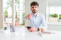 Young business man using smartphone sending a message pointing with finger to the camera and to you, hand sign, positive and Royalty Free Stock Photo
