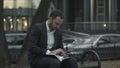 Young business man working with papers and phone at green park, waiting for meeting, Royalty Free Stock Photo