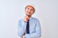 Young business man wearing contractor safety helmet over isolated background with hand on chin thinking about question, pensive Royalty Free Stock Photo