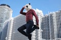 Young business man wearing a panda head mask, jumping in front of the corporate buildings Royalty Free Stock Photo