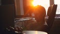 Young business man working on a computer at home through the sun, in view of the profile against the window during Royalty Free Stock Photo