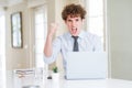 Young business man working with computer laptop at the office angry and mad raising fist frustrated and furious while shouting Royalty Free Stock Photo